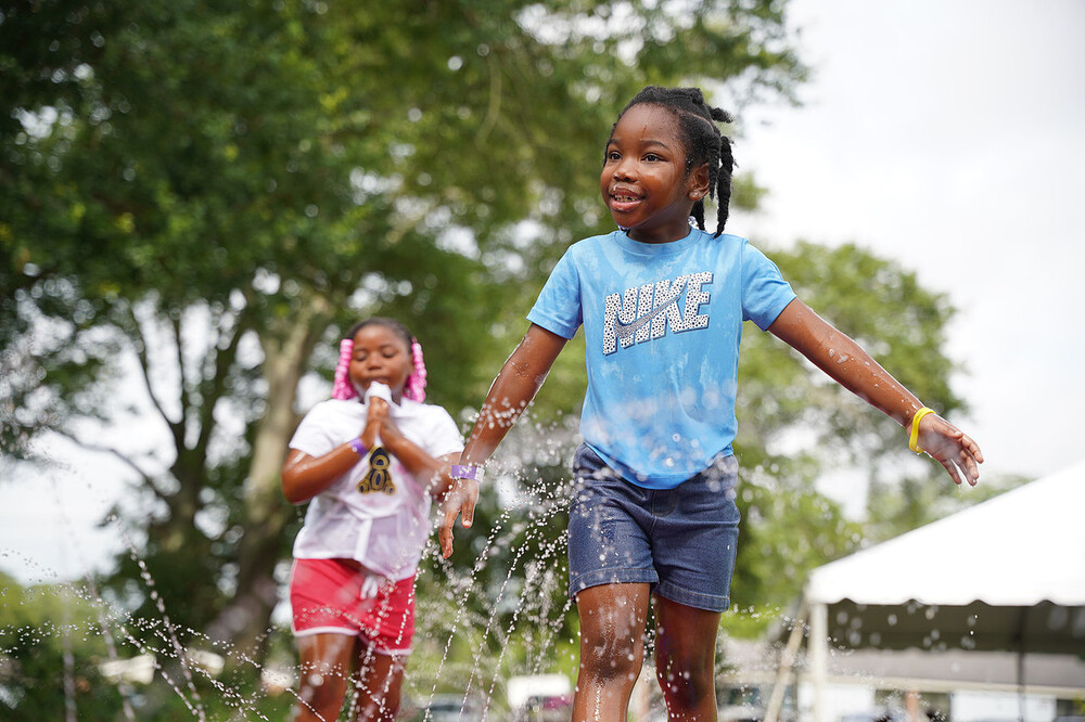 Two girls playing in a sprinkler.