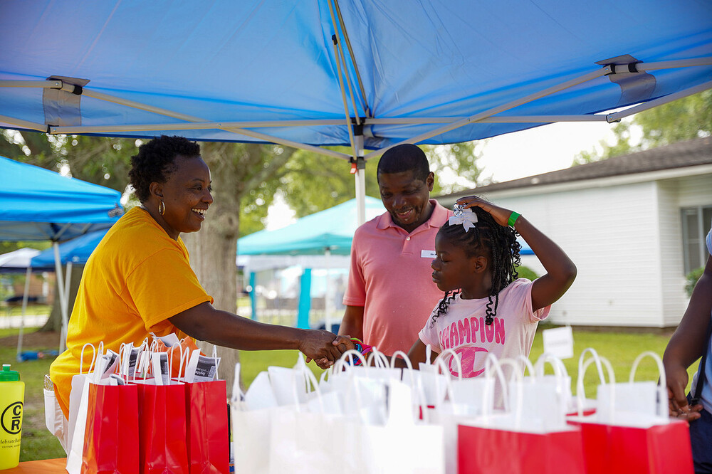 Two adults talking to a young girl in a tent.