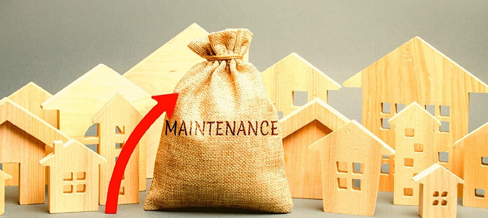 A sack cloth bag with the word Maintenance on it with a red arrow pointing to it surrounded by many wooden houses