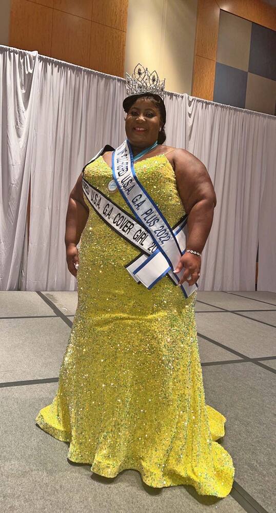 Seneca Clark smiles brightly while wearing 2 sashes and the winning tiara. 