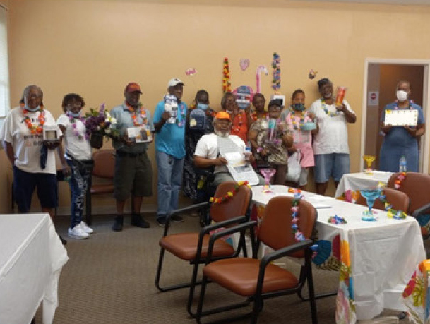 Elderly Village residents all stand together and show off the prizes that they won during bingo.