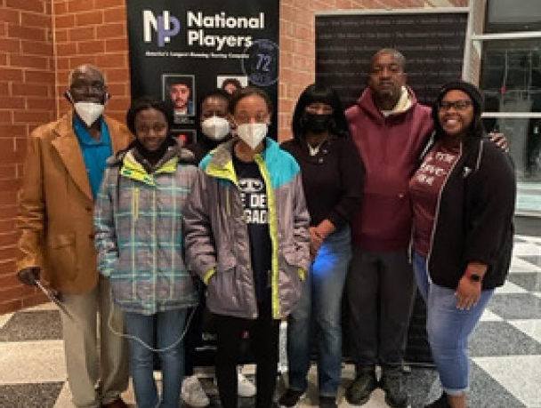 Seven residents wearing face masks all gather together in the lobby for a group photo.