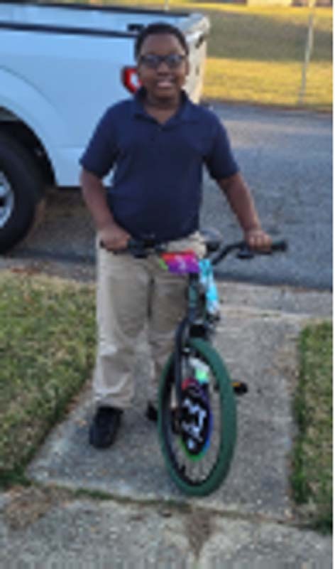 A young boy holding his brand new bike. 