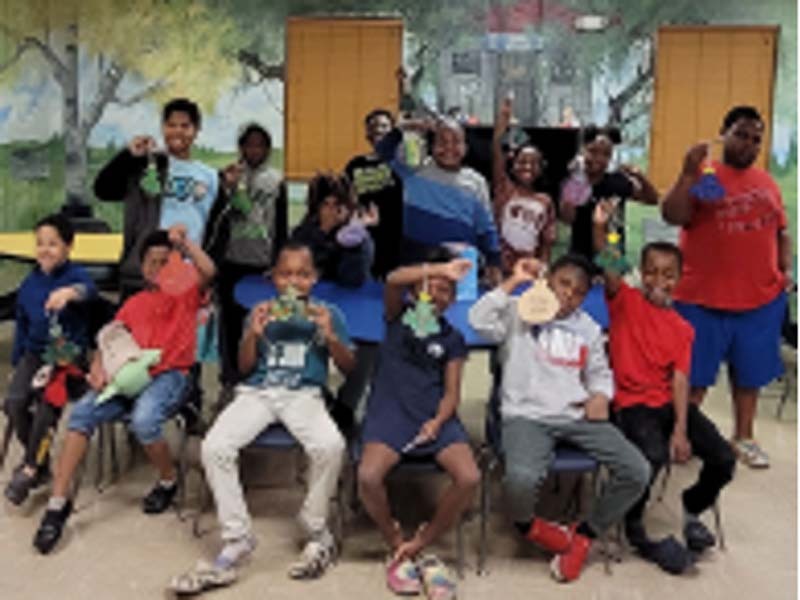 Many children are holding up their ornaments to the camera.