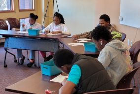 Youth sitting at desks working on an art activity.