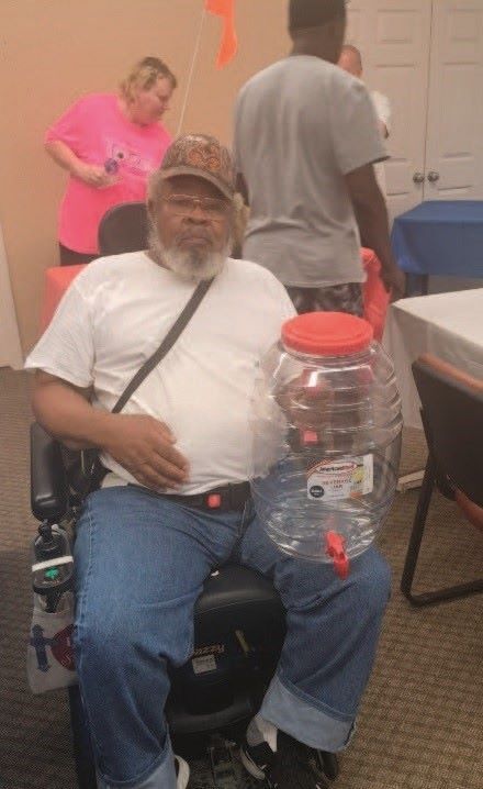 Senior gentleman in a wheelchair showing a beverage dispenser as his bingo prize. 