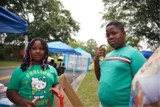 Two kids in green shirts standing for a picture.
