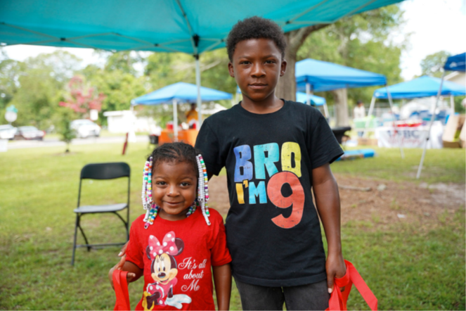 A boy and young girl stand under a tent for a picture.