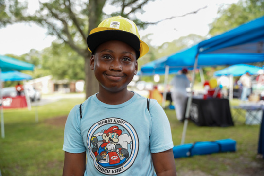 A young boy stands and smiles.