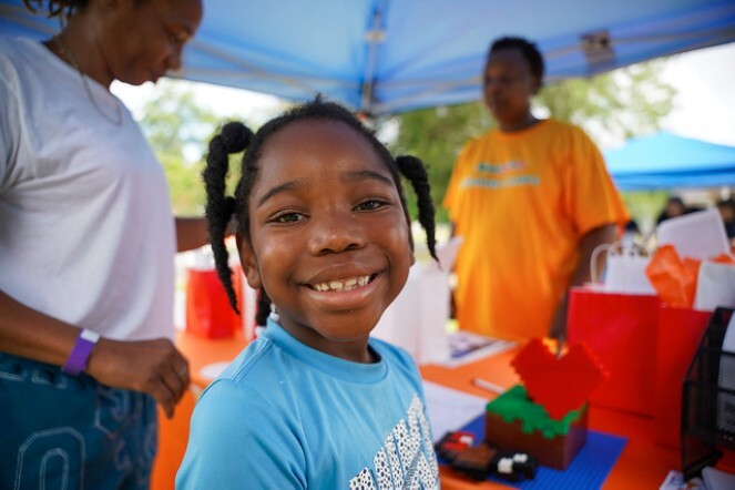 A young girl stands and smiles.