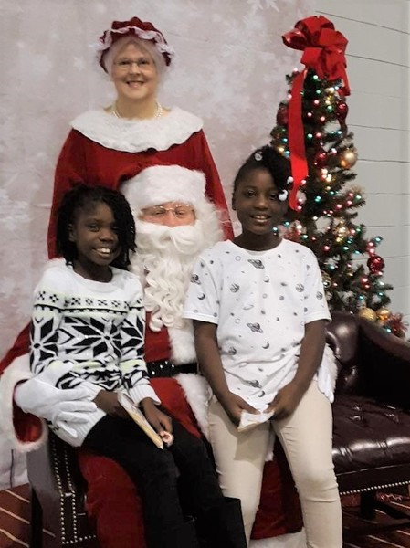 2 little girls on Santa\'s lap with Mrs. Claus standing behind him