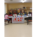 A resident sits at a table and talks with two women who are wearing masks.