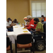 A resident in a motorized wheelchair is seated at a table playing bingo with other residents.