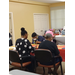 Many residents are seated at tables and looking down intently at their game of bingo. 