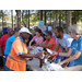 A volunteer behind the ice-cream table extends a napkin out to a resident who is holding a cup of ice-cream in his hand. 