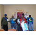 A group of six residents all stand together and show their bingo prizes to the camera. 