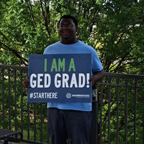 A man holding a GED Grad sign.