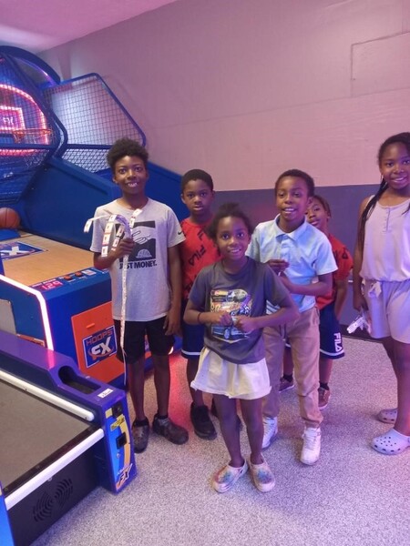 Kids standing in front of a game at an arcade.