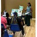  A woman smiling and handing out pieces of information to a room full of people. 
