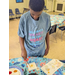  A boy standing and painting at a table. 