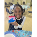 A girl smiling for a picture with a painting of a wave that she made. 