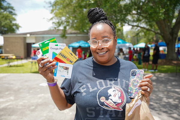 A woman smiling and holding gift cards that she won.
