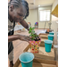  A woman planting a plant in her newly painted pot. 